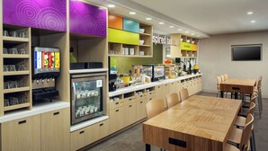 Un restaurante moderno con una larga barra, diversas opciones de asientos y una variedad de dispensadores de comida y bebida.