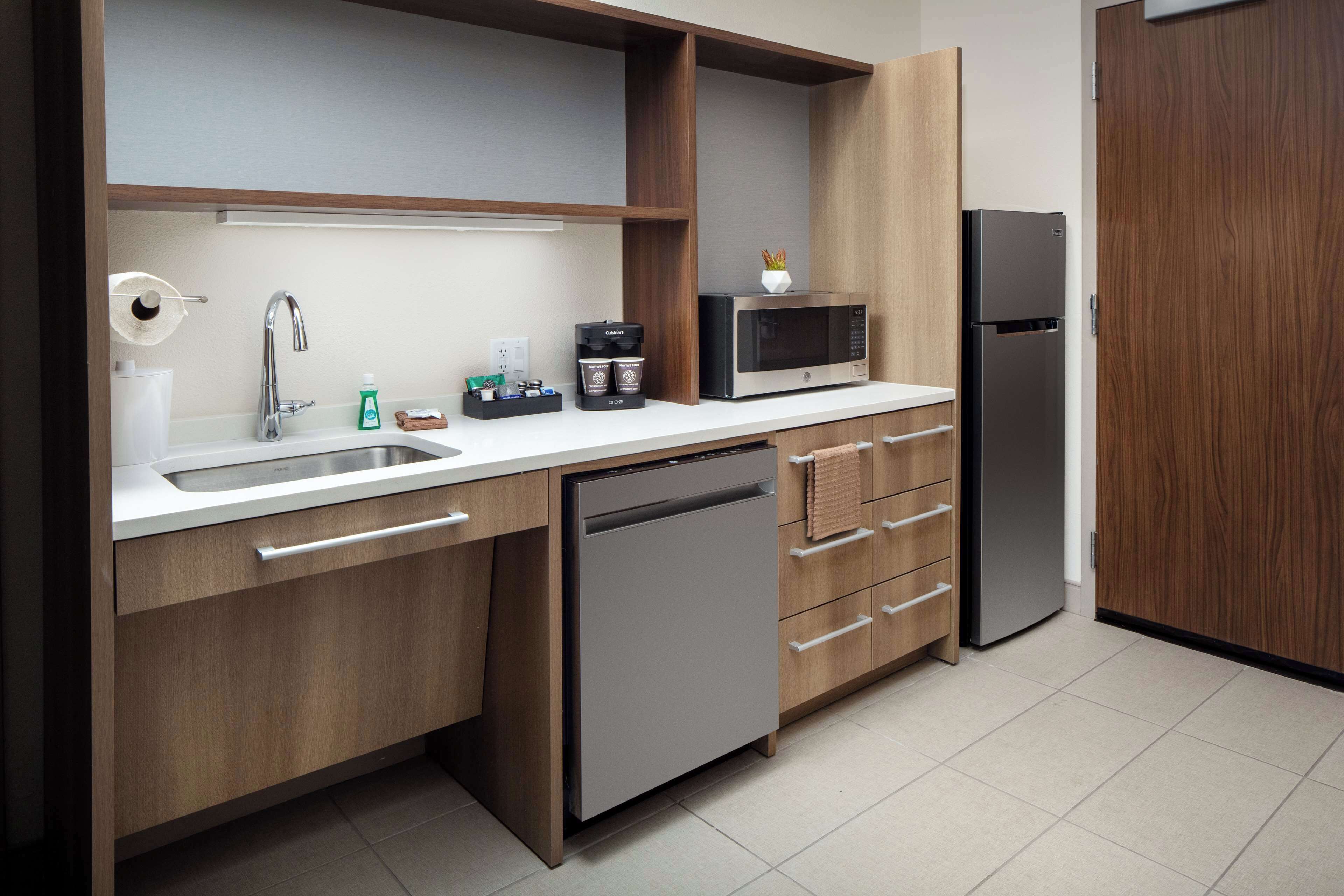 Uma cozinha moderna equipada com lava-louças, micro-ondas, frigorífico e máquina de café.