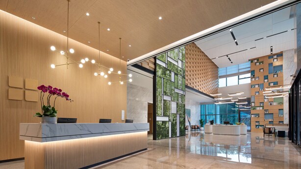A modern reception area with a marble counter, a potted plant, and a unique geometric wall design. - Hilton Garden Inn Shenzhen Guangming Hongqiao Park (Shenzhen)