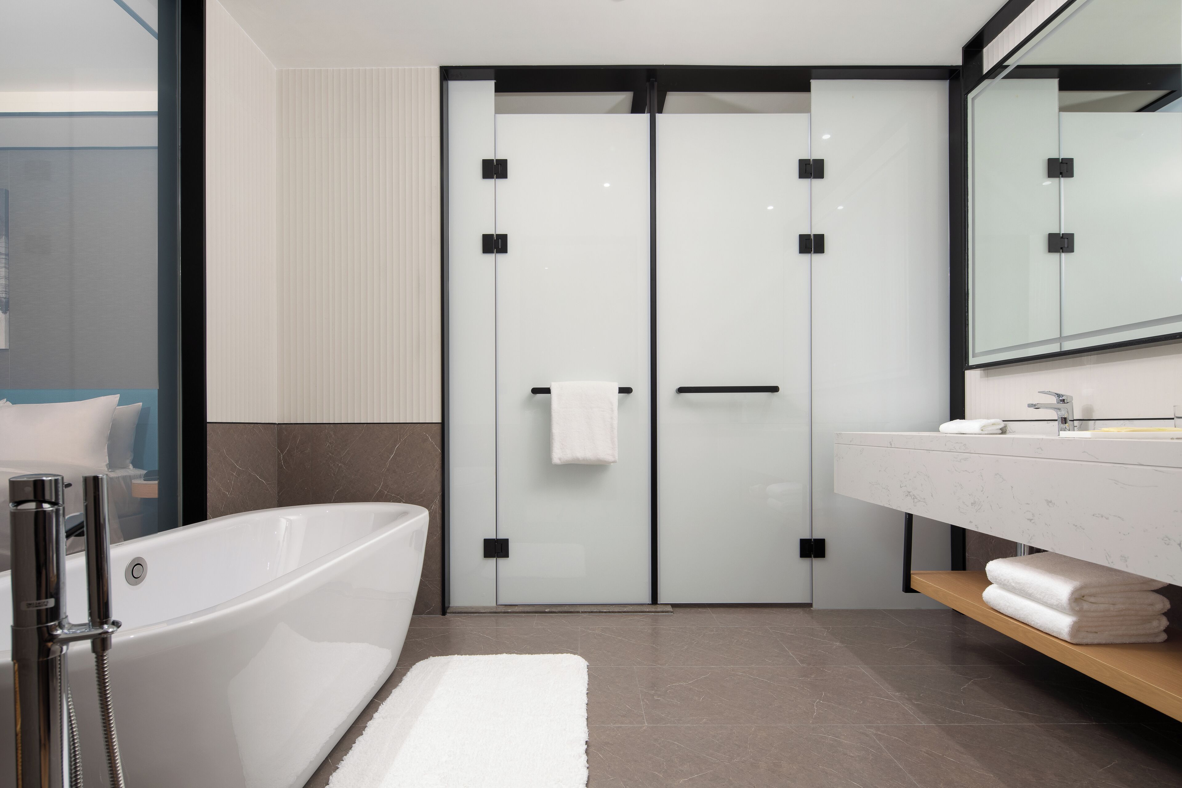 Een moderne badkamer met een vrijstaand bad, een douche met glazen wanden en een wastafel met spiegel.