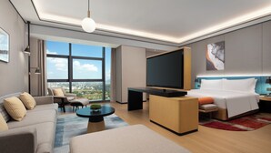 A modern hotel room with a large bed, a sofa, a TV, and a city view. - Hilton Garden Inn Shenzhen Guangming Hongqiao Park (Shenzhen)