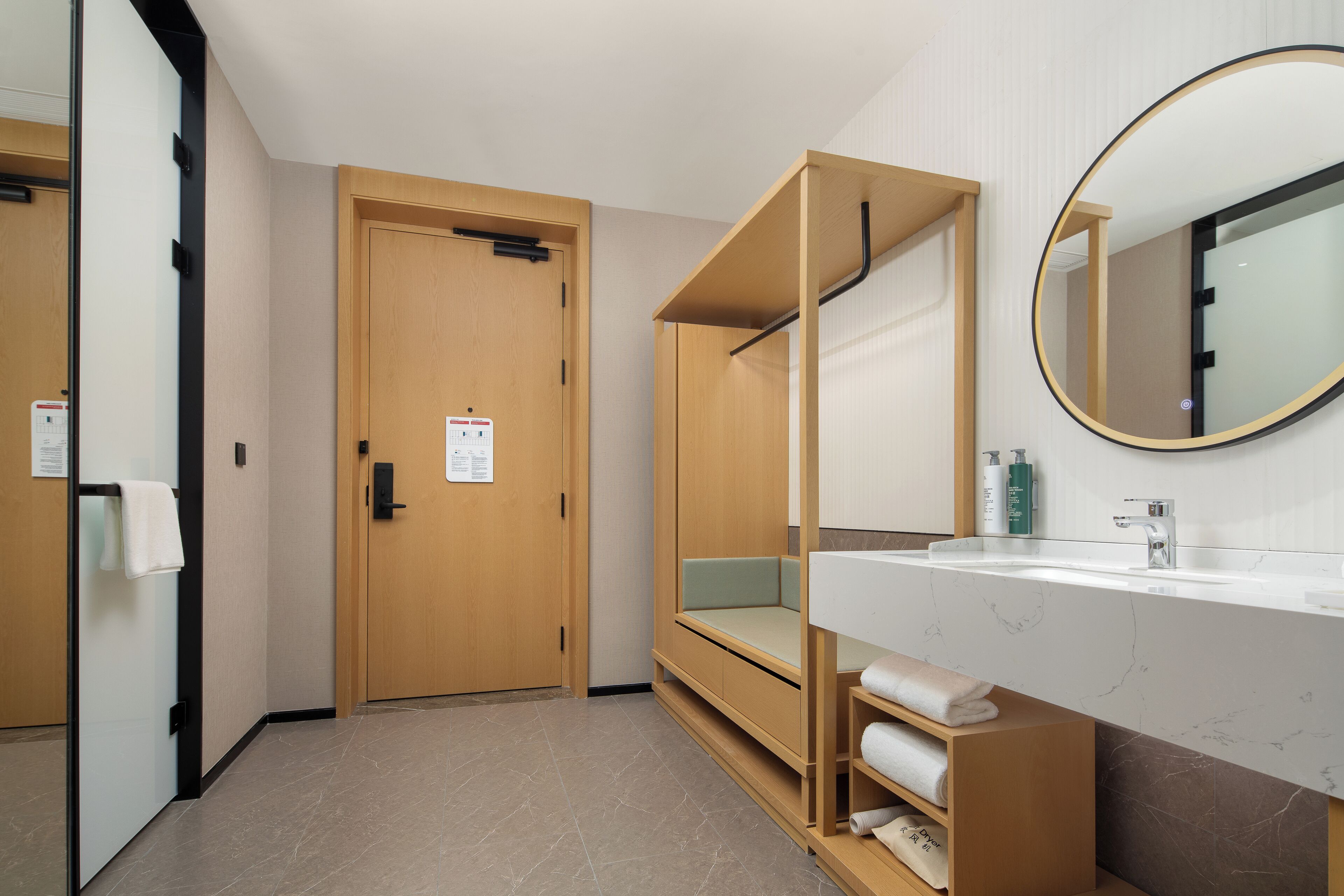 A modern bathroom with a wooden bench, a sink with a marble countertop, and a large mirror.