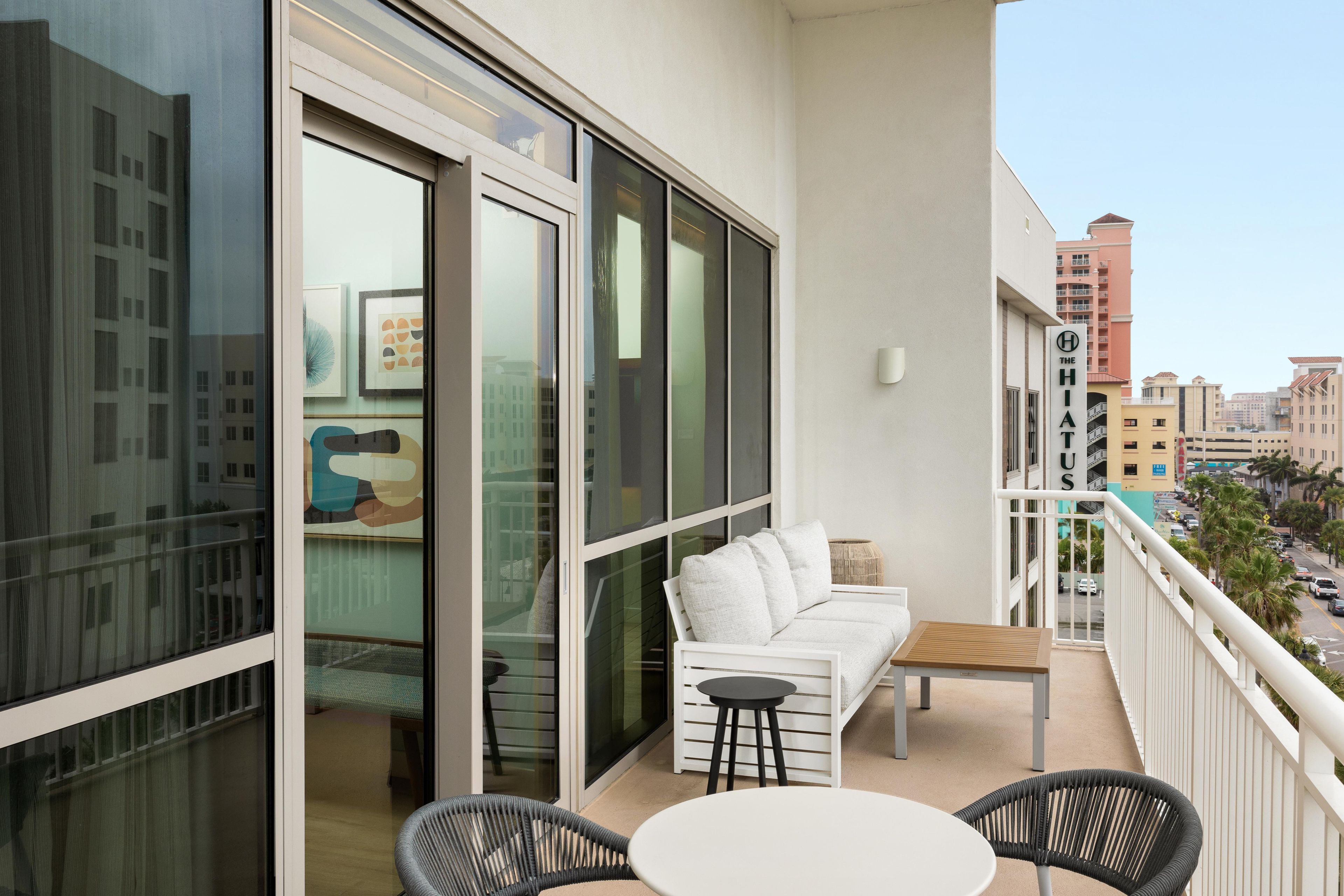A balcony with a white sofa, two chairs, and a small table.