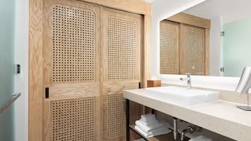 A modern bathroom with a wooden vanity, a large mirror, and a sink.