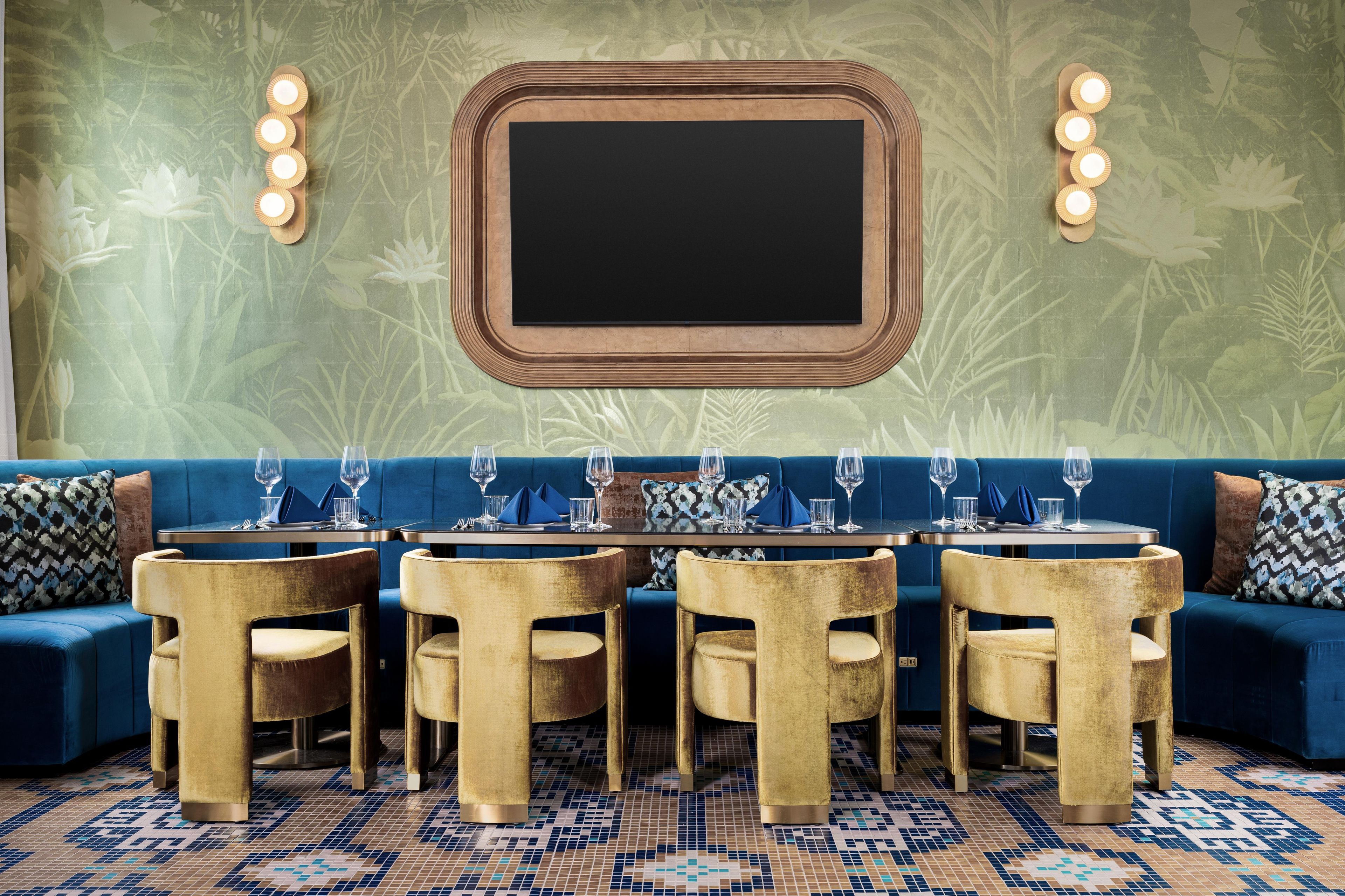 A dining area with a round table, six chairs, and a blue sofa.