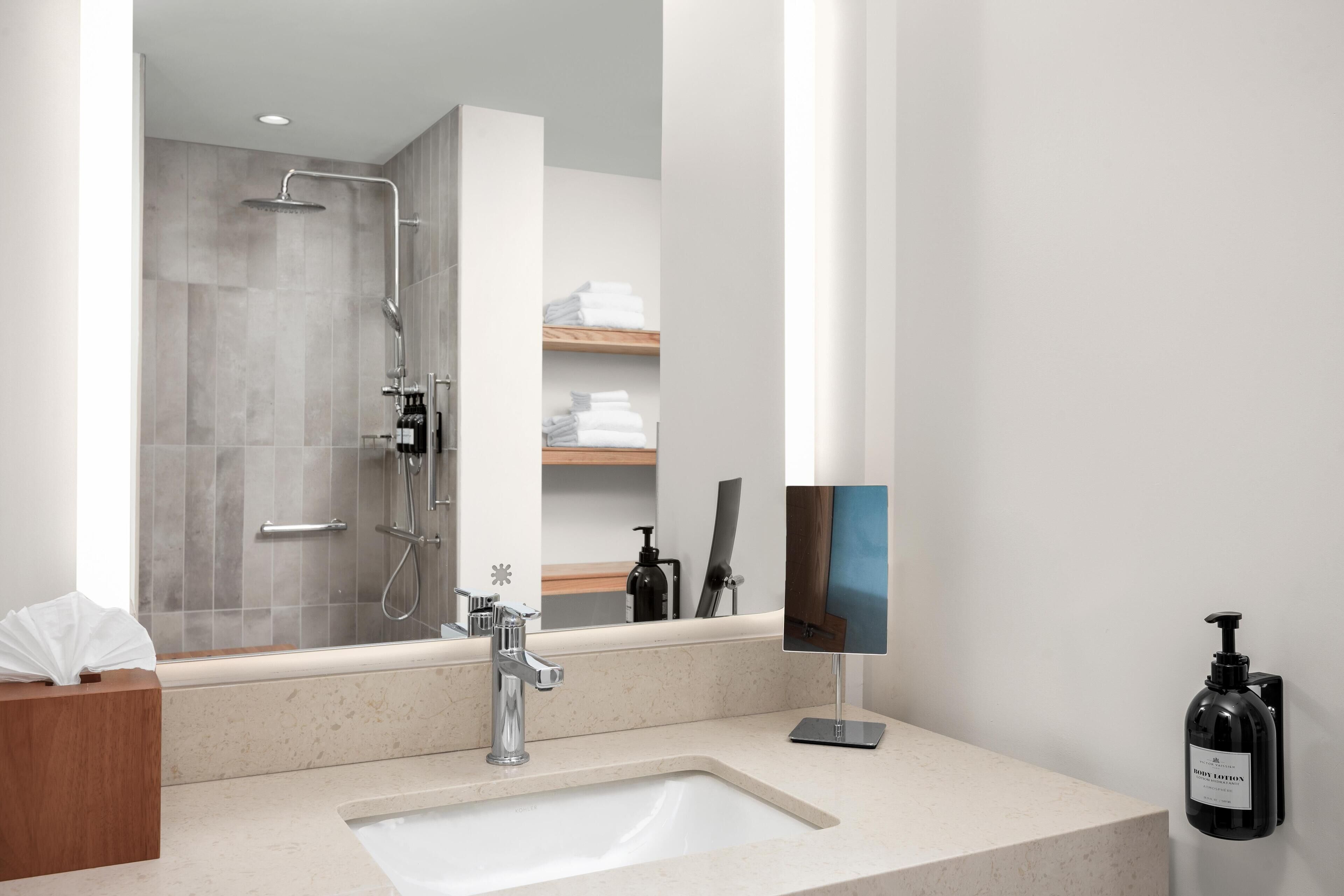 Une salle de bain moderne avec un grand miroir, un lavabo et une douche.