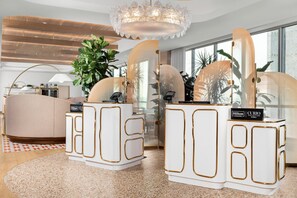 A modern hotel lobby with a large plant, a round seating area, and a chandelier.