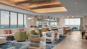 Een ruime lounge met een bar, zitgedeeltes en grote ramen met uitzicht op zee.