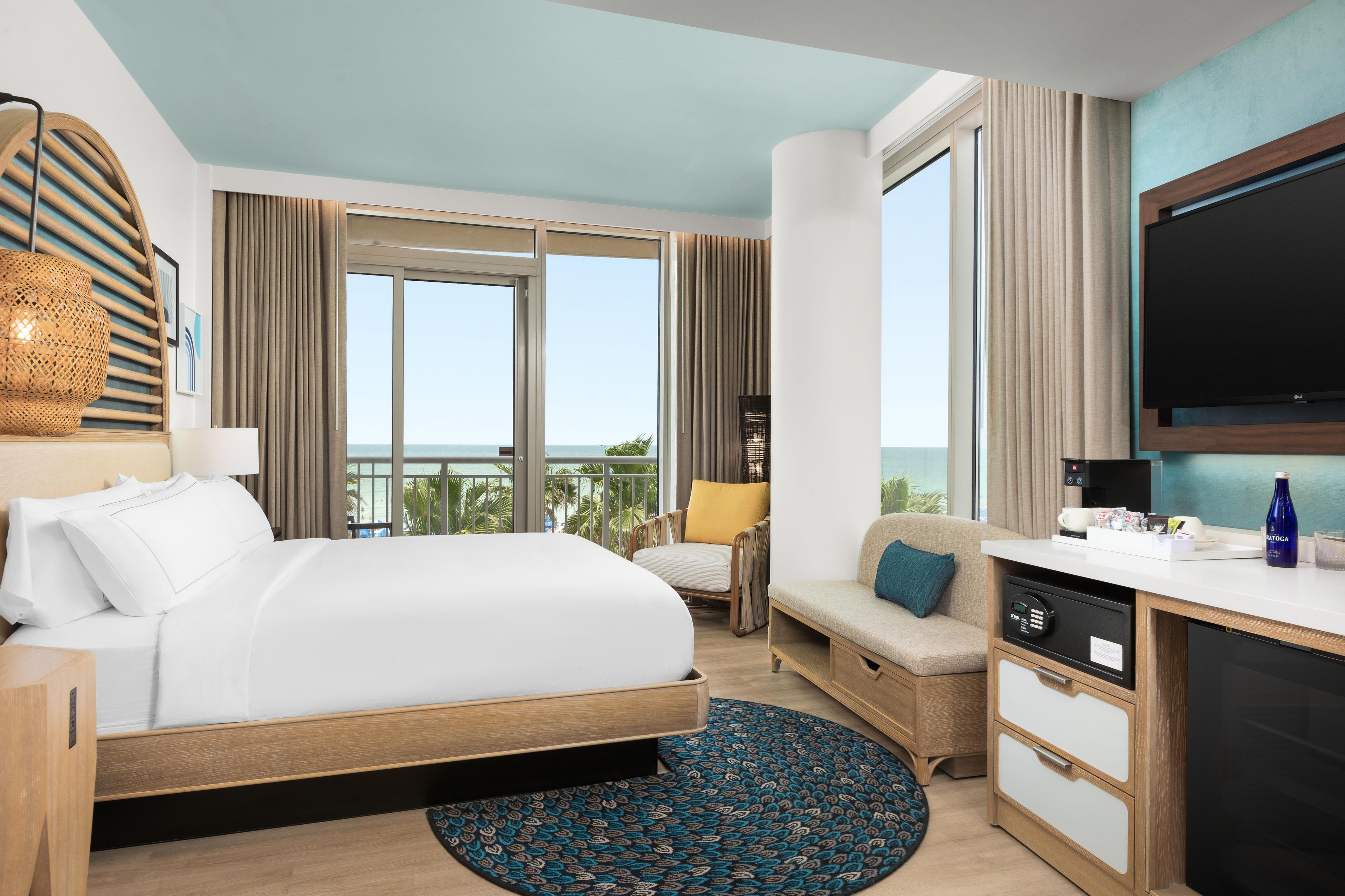 Una habitación de hotel con una cama, un escritorio, un televisor y vistas al océano.