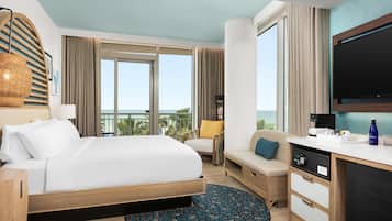 Una habitación de hotel con una cama, un escritorio, un televisor y vistas al océano.