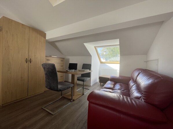 A compact room with a wooden wardrobe, a desk with a computer, a leather sofa, and a skylight. - Eurotel am Main (Offenbach am Main)