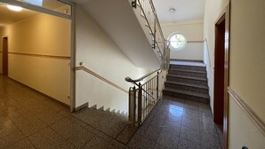 A staircase with a handrail, a landing with a door, and a circular window at the top. - Eurotel am Main (Offenbach am Main)