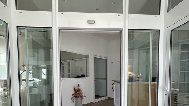 A modern interior with a central open space, glass doors, a wooden bench, and a potted plant. - Eurotel am Main (Offenbach am Main)