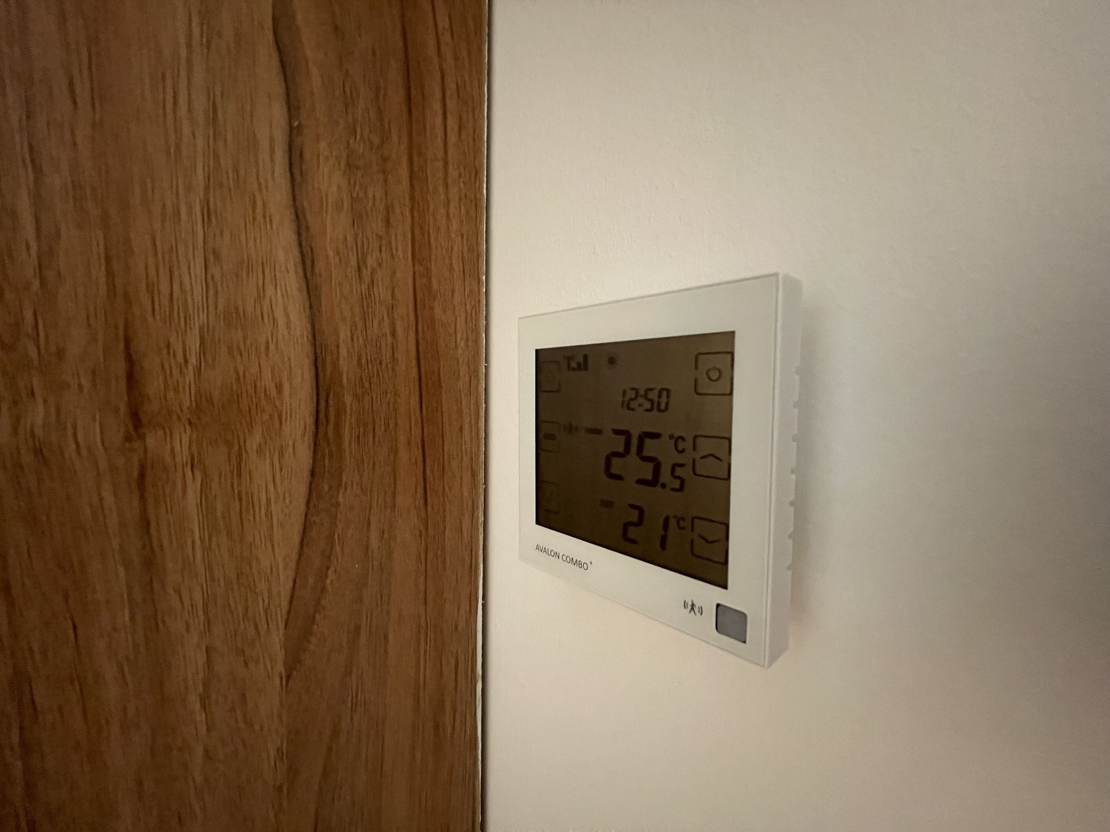A thermostat on a wall displaying the temperature as 25.5°C.