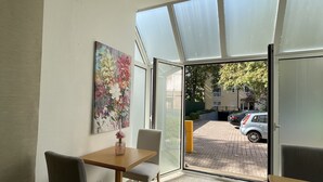 A modern dining area with a table and chairs, a painting on the wall, and a view of the street outside. - Eurotel am Main (Offenbach am Main)