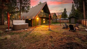 A cozy cabin with a hot tub, outdoor seating, and a deck.