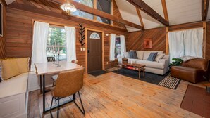 A cozy cabin interior with a dining area, sofa, and a fireplace.