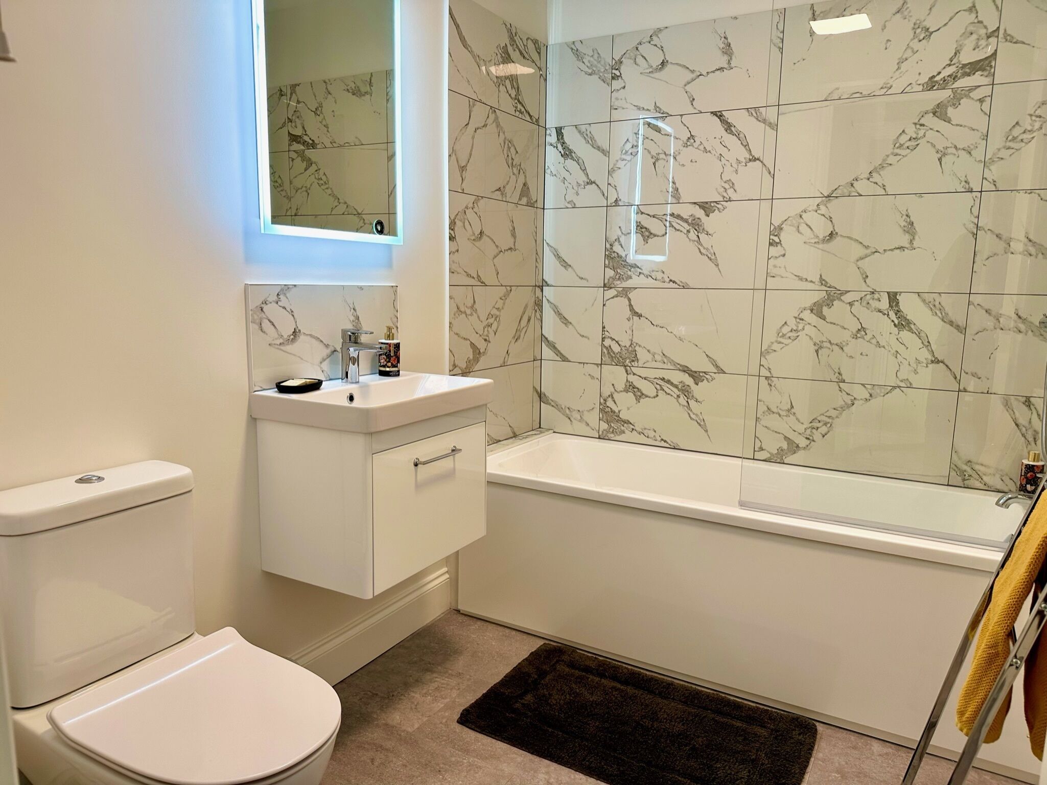 A modern bathroom with a toilet, sink, and bathtub.