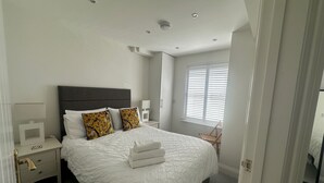 A bedroom with a bed, nightstands, a lamp, and a window with blinds. - House by the Sea, Worthing. (Worthing)