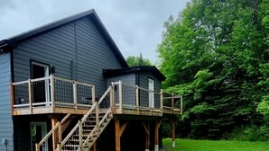 A house with a wooden deck, outdoor seating, and a fire pit.