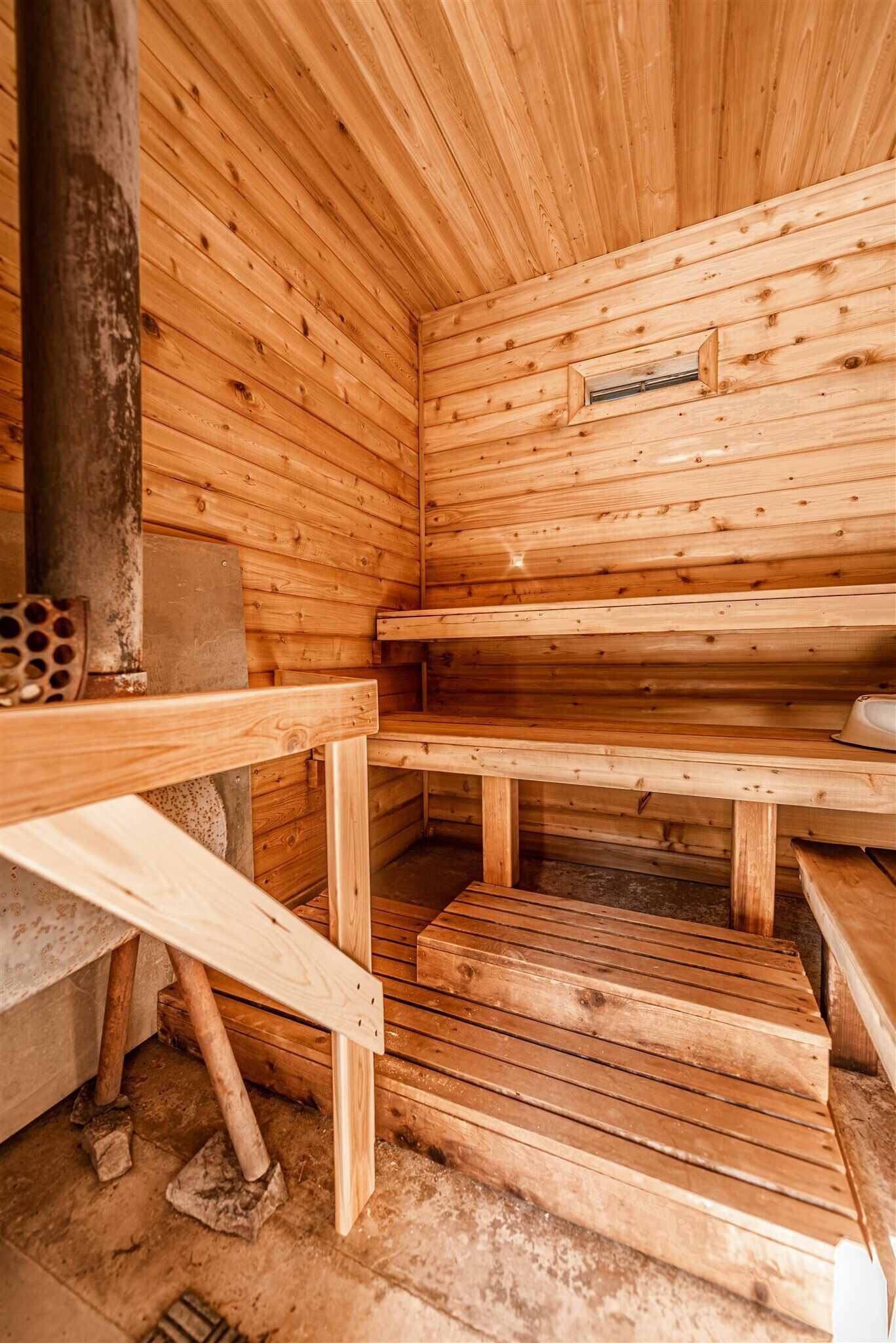 A wooden sauna with benches and a small window.