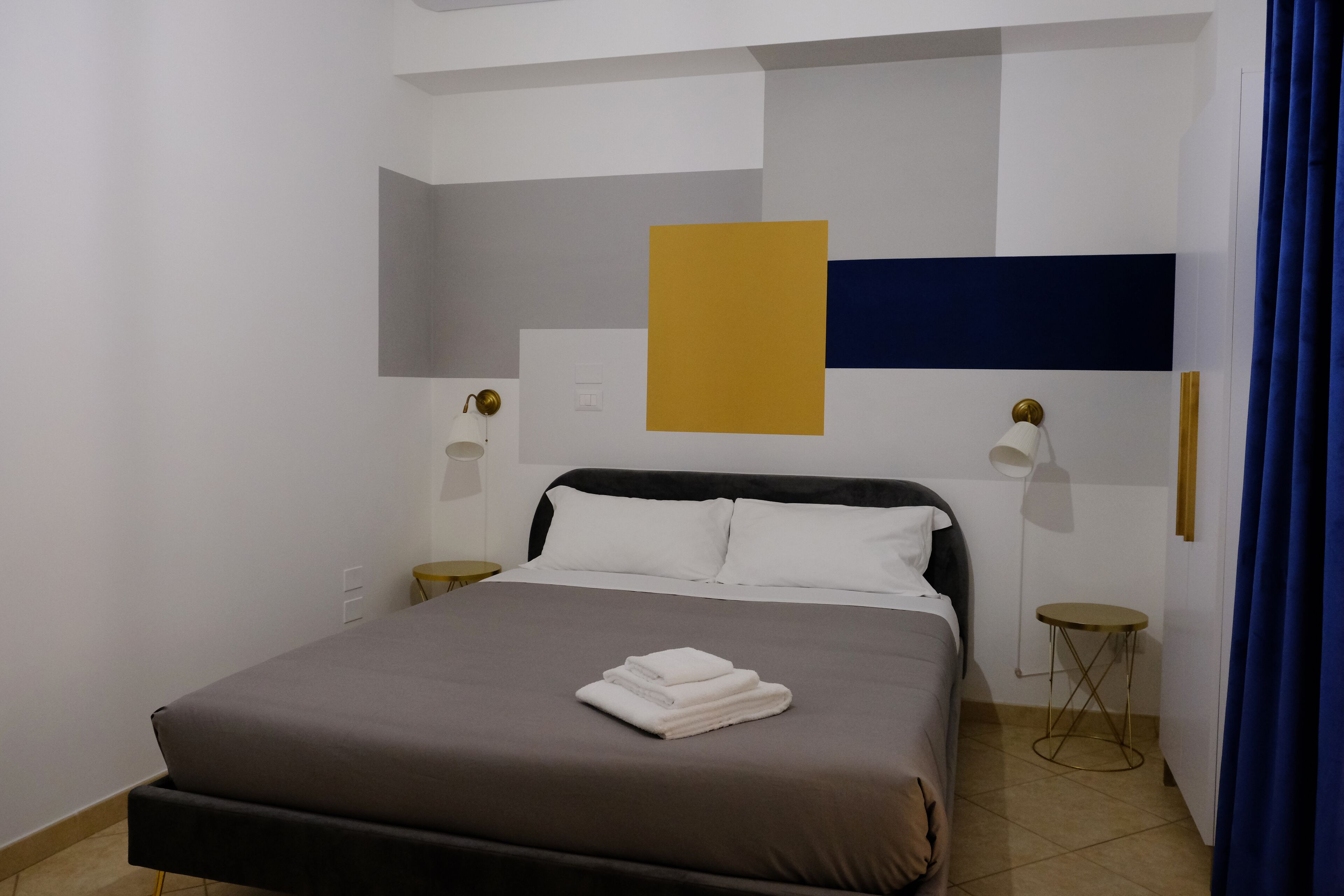 A modern bedroom with a bed, bedside tables, and a wall-mounted lamp.