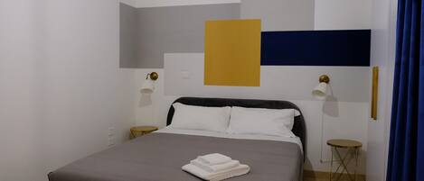 A modern bedroom with a bed, bedside tables, and a wall-mounted lamp.
