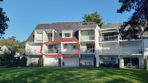 Un immeuble résidentiel à plusieurs étages, doté d’un grand portail de garage, d’un balcon et d’une pelouse bien entretenue.
