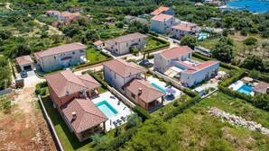 Un barrio residencial con casas, una piscina y vista al mar.