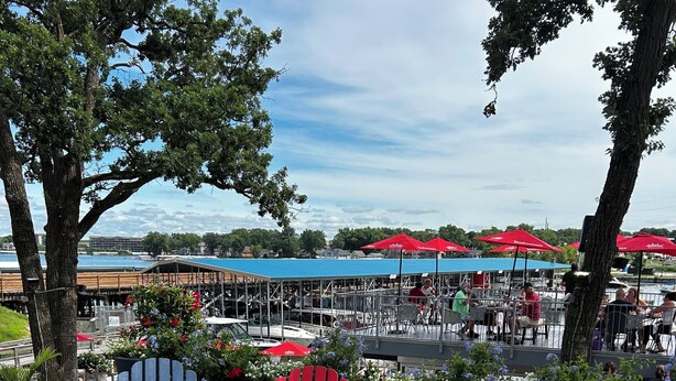 Outdoor seating with Adirondack chairs, a fire pit, and a view of a waterfront restaurant. - Premier Location! Lake View! (Arnolds Park)