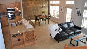 A modern kitchen with a central island, dining area with a table and chairs, a black leather sofa, and a window with a view. - Premier Location! Lake View! (Arnolds Park)