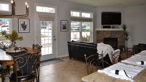 A dining area with a long table, chairs, and a fireplace. There are framed pictures on the wall and a TV mounted above the fireplace. - Premier Location! Lake View! (Arnolds Park)