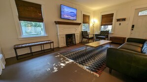 A living room with a fireplace, a television, a sofa, and a bench. - 2BR Craftsmen Greenlake Home + Backyard + Firepit (Seattle)
