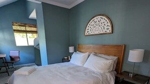 A bedroom with a large bed, two bedside tables with lamps, a wooden headboard, and a decorative wall piece. - 2BR Craftsmen Greenlake Home + Backyard + Firepit (Seattle)