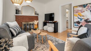 Ein modernes Wohnzimmer mit Kamin, Fernseher und einem großen abstrakten Gemälde.