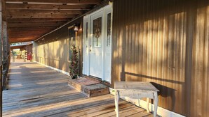 A wooden porch with a bench and a small table, leading to a white door with a star-shaped window. - Country Living located Mid-Way between Granbury and Glen Rose.  (Granbury)