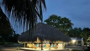 A thatched-roof structure with outdoor seating, surrounded by palm trees and a clear sky. - HOTEL LAS CASITAS DE MAR ADENTRO  (Rosario Islands)