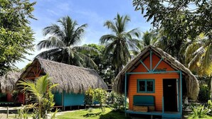 A thatched-roof hut with a small porch and a colorful wooden structure nearby. - HOTEL LAS CASITAS DE MAR ADENTRO  (Rosario Islands)