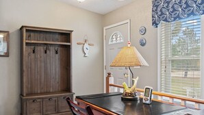 Een eetruimte met een houten tafel, stoelen, een lamp en een decoratief beeld van een vogel.