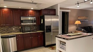 Una cocina moderna con electrodomésticos de acero inoxidable, armarios de madera oscura y una isla central con letreros decorativos.