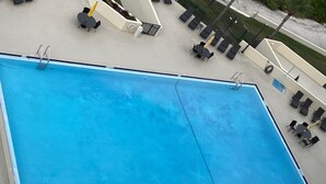 Una gran piscina rectangular con un trampolín y escalones.