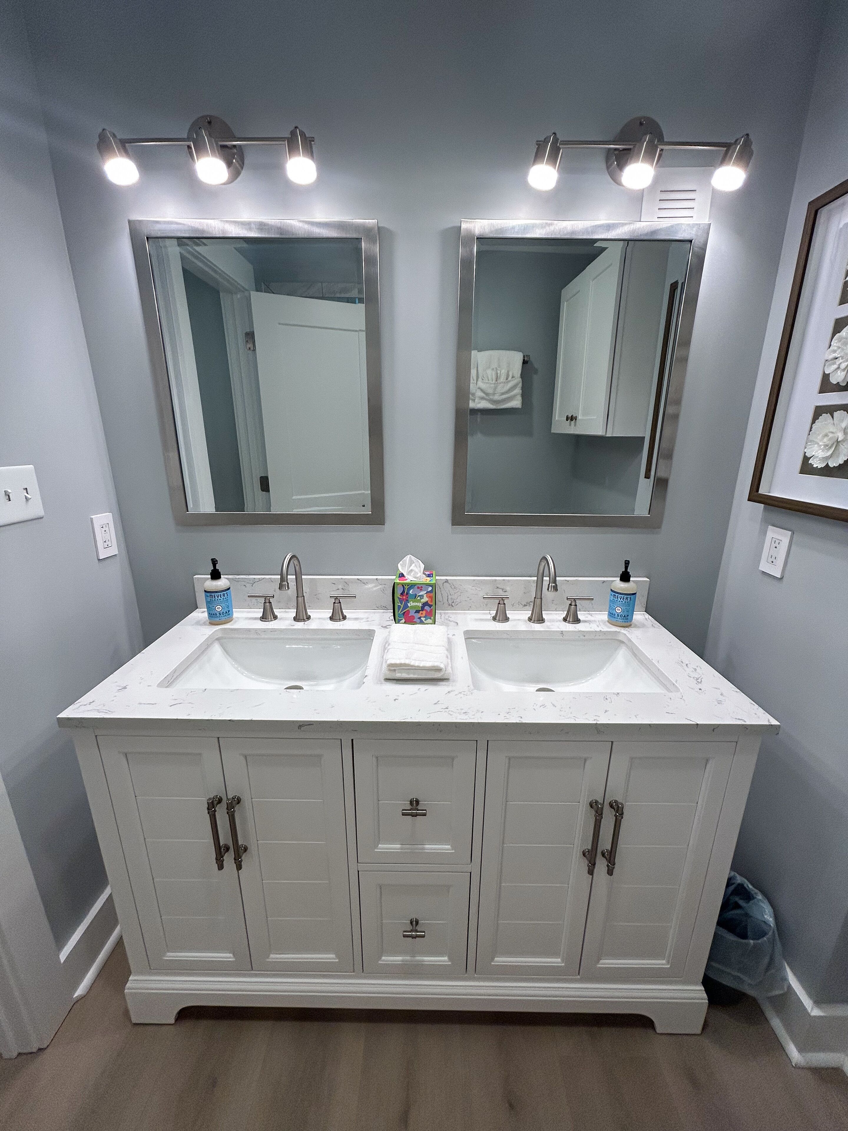 A bathroom with two sinks, a mirror, and overhead lighting.