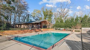 Una piscina rectangular con muelle de madera y cerramiento de metal.