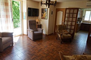 Uma sala de estar com sofá, poltrona e um aparador de madeira.