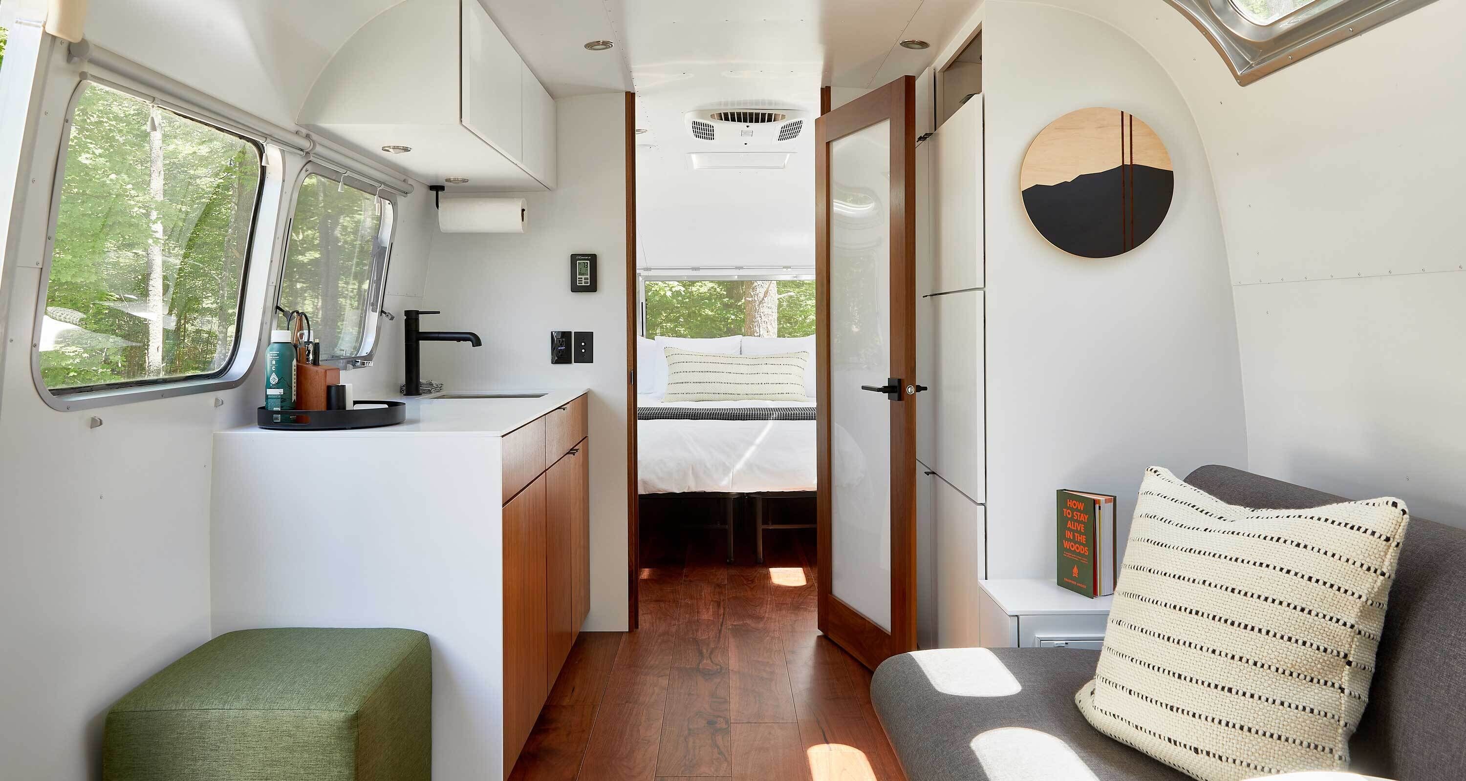 En kompakt autocamper indretning med et tekøkken, en seng og et siddeområde.