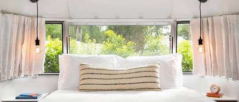 Un dormitorio con una cama grande, dos mesitas de noche, una ventana con cortinas y vistas al exterior.