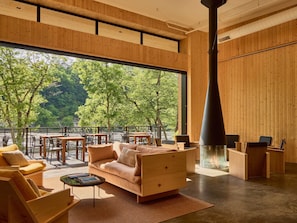 A modern interior with a large window, wooden furniture, and a fireplace.