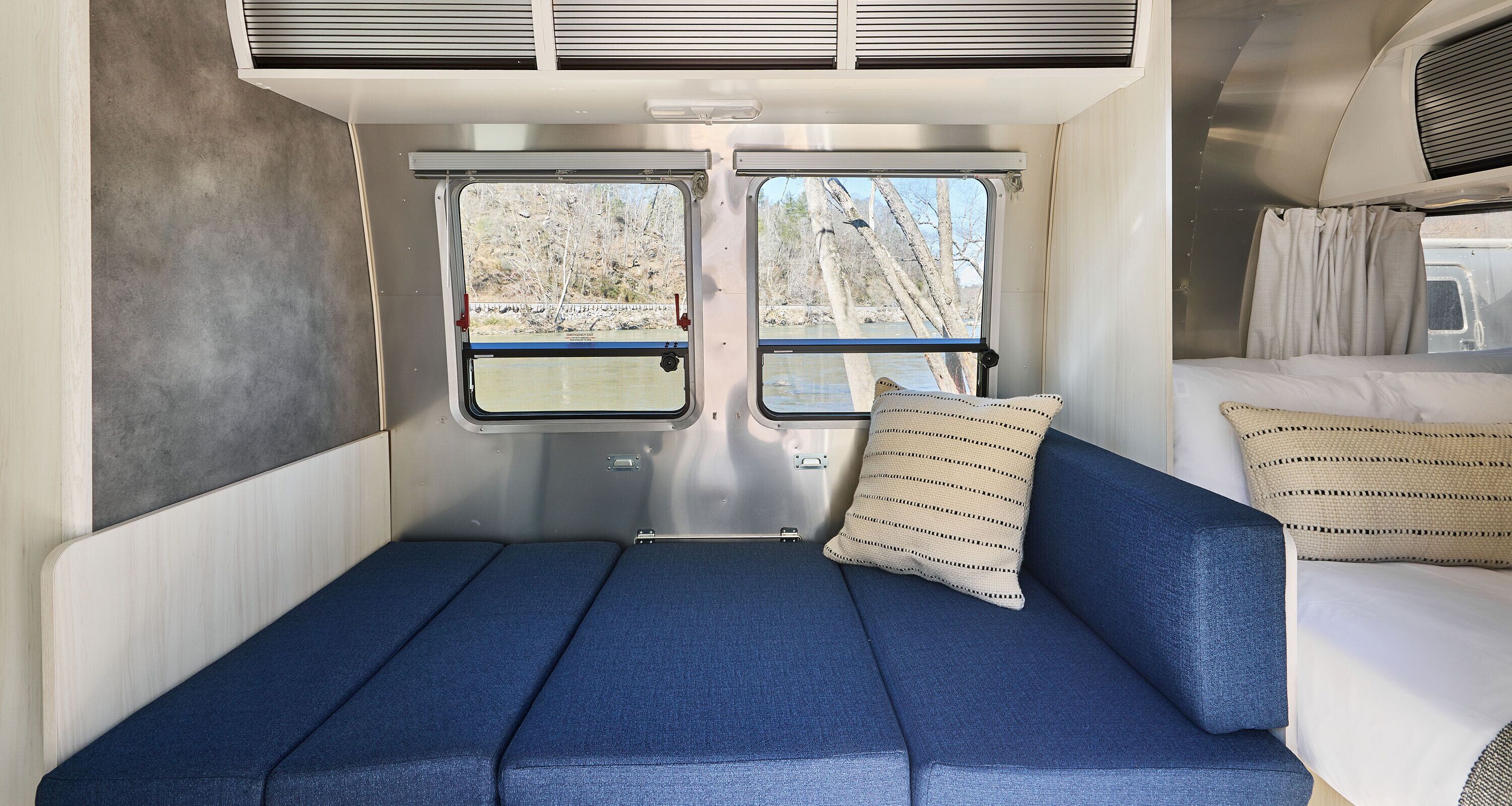 A compact interior with a blue sofa, a small window, and a bed with white bedding.