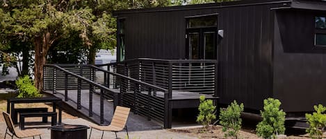 A modern black building with a balcony and outdoor seating area.
