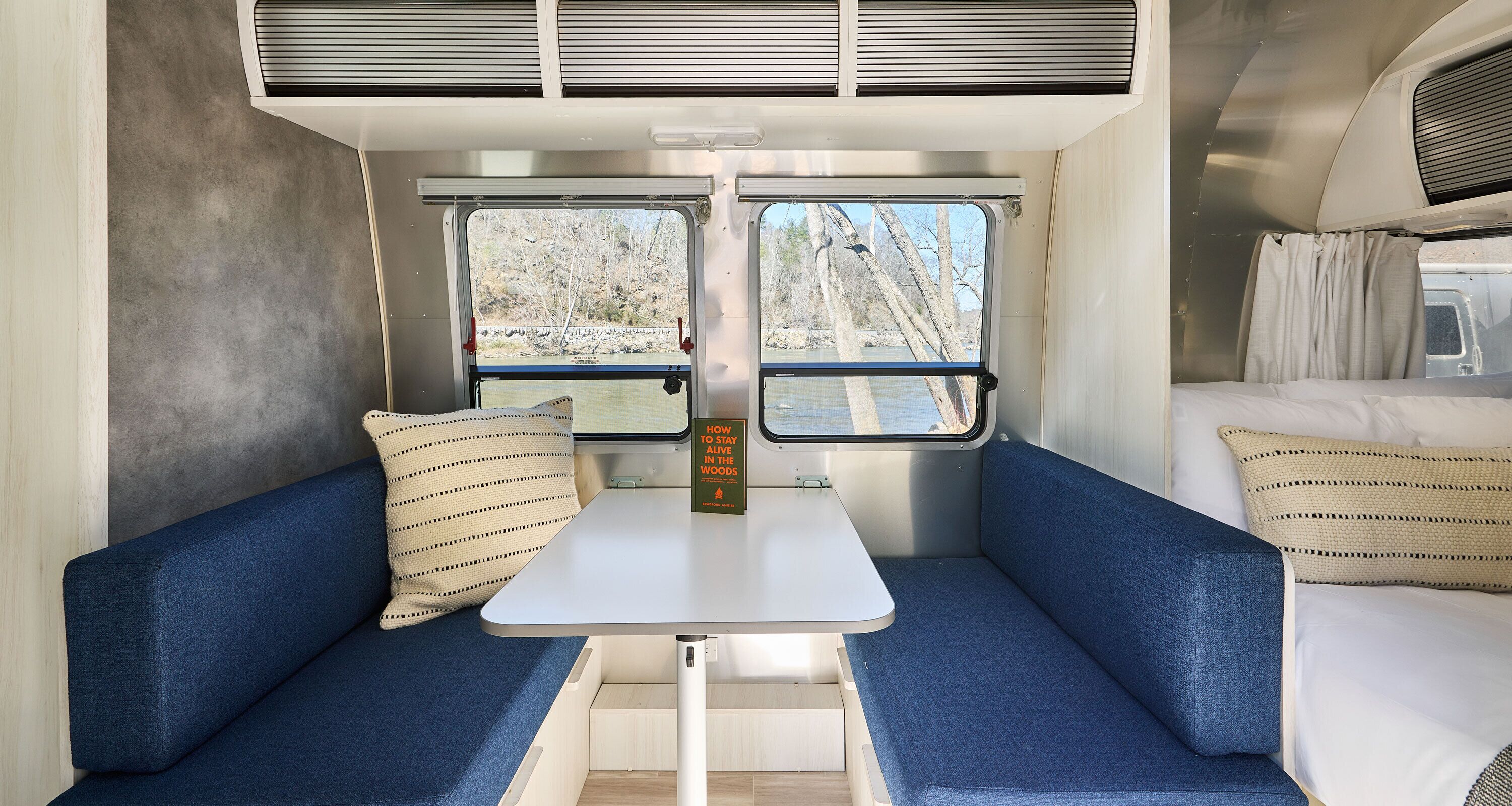 A compact interior with a sofa, a small table, and a window offering a view of trees.